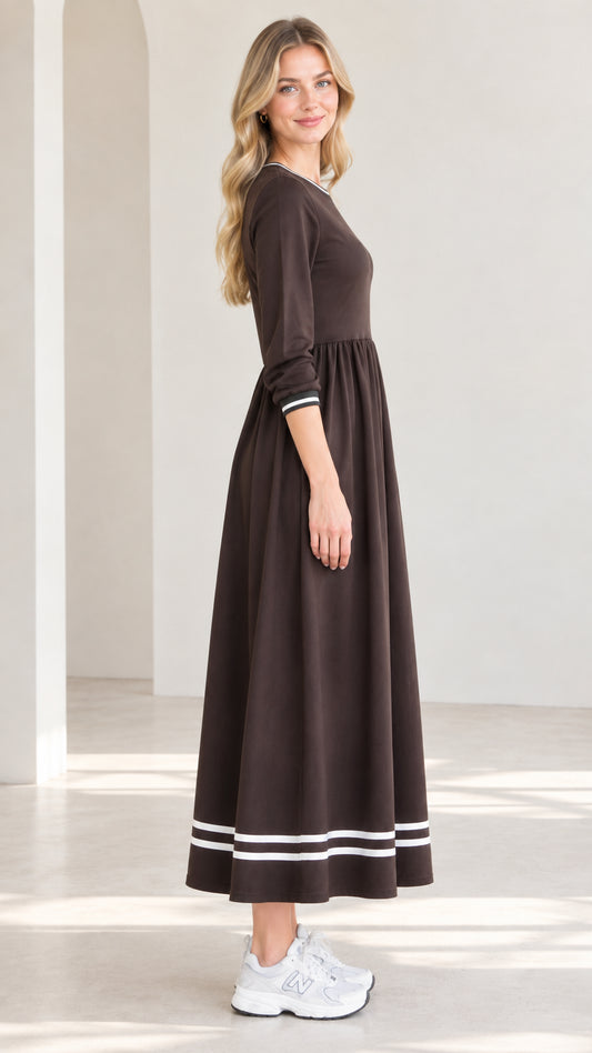 Side profile view of woman modeling brown contrast stripe trim maxi dress