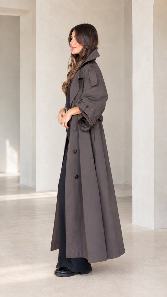 Side profile view of woman wearing charcoal brown full-length trench coat