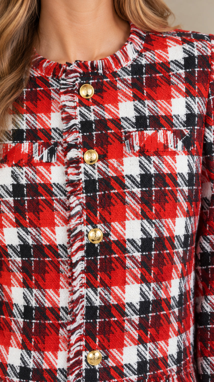 Close-up detail of textured red plaid tweed, gold embossed buttons, and fringe trim