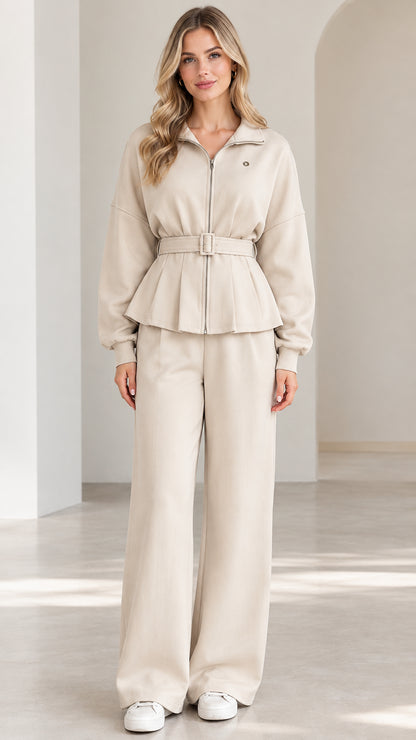 Front full-length view of woman wearing beige zip-up belted peplum jacket and wide-leg lounge pants