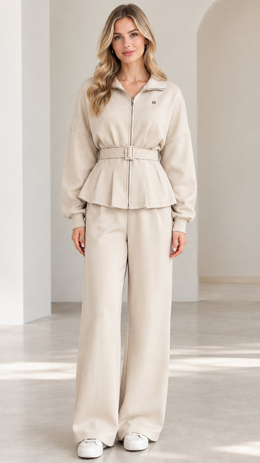 Front full-length view of woman wearing beige zip-up belted peplum jacket and wide-leg lounge pants