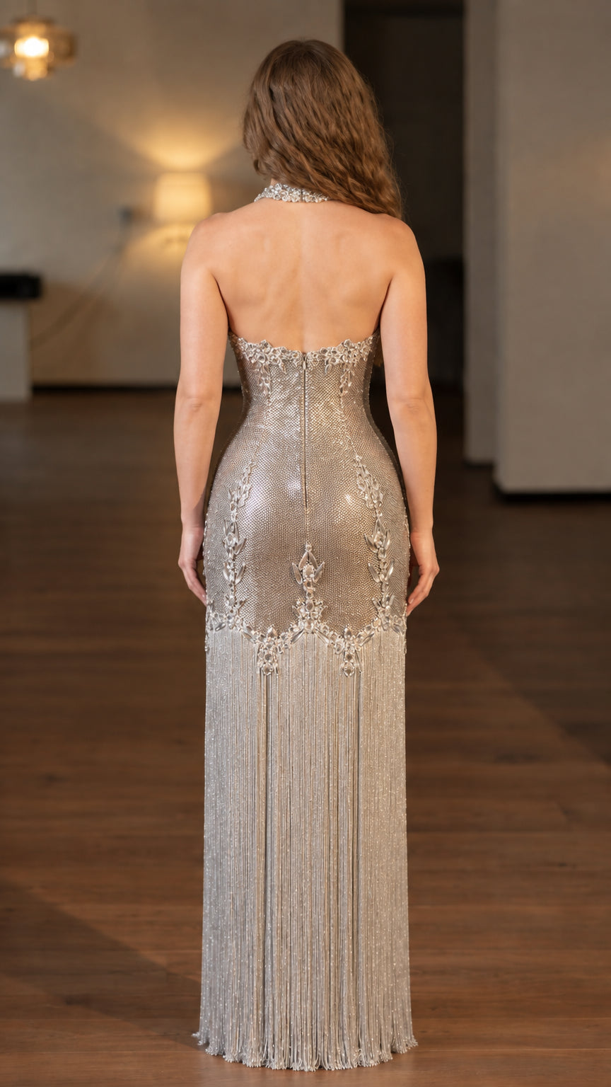Back view of model showing open back silhouette of silver beaded fringe formal dress