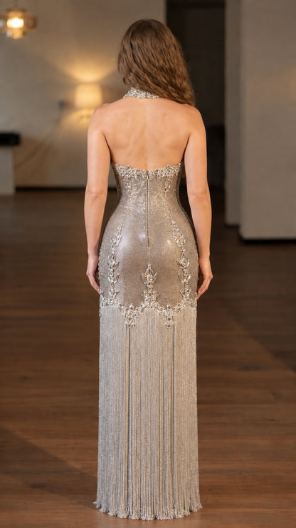 Back view of model showing open back silhouette of silver beaded fringe formal dress