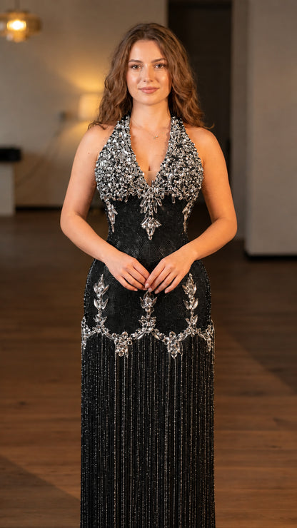 Model wearing black rhinestone embellished halter fringe maxi evening gown