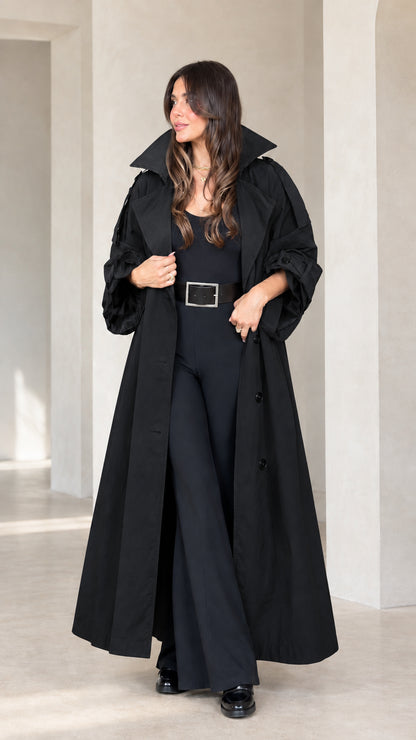 Front view of woman wearing black maxi trench coat over black jumpsuit